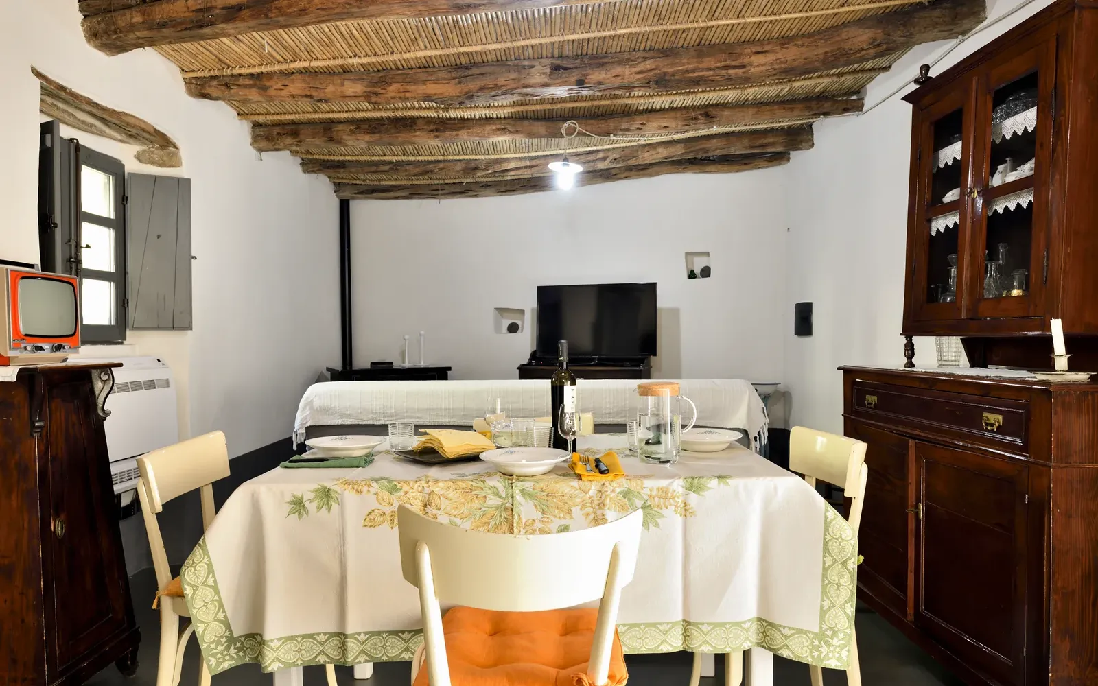 Zona giorno con travi a vista, credenza e televisore d’epoca