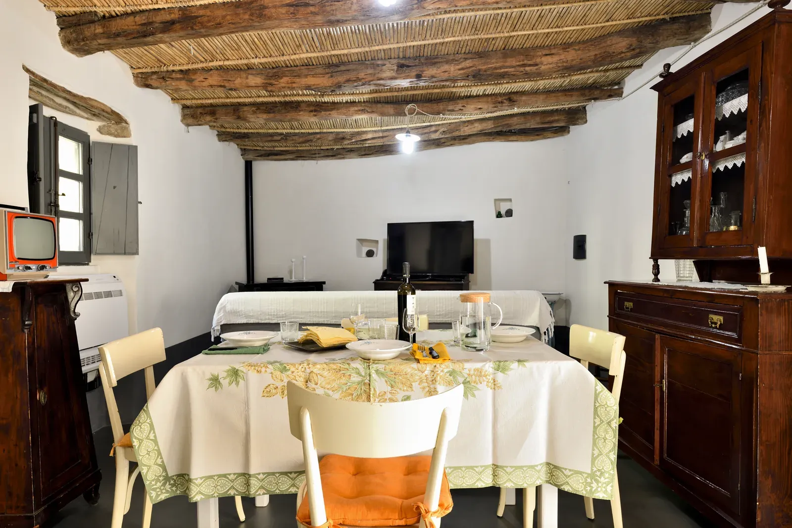 Zona giorno con travi a vista, credenza e televisore d’epoca