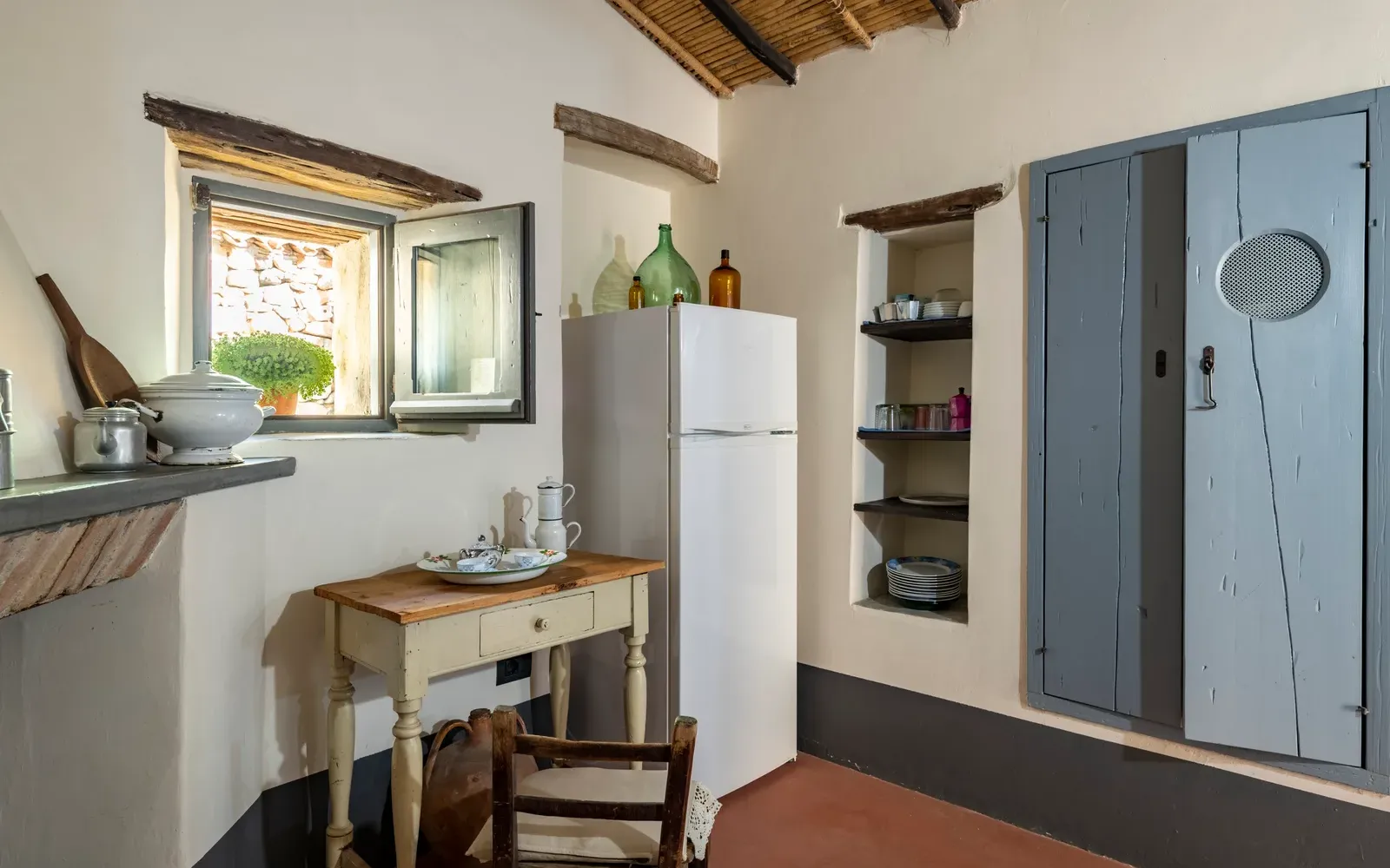 Angolo cucina con frigorifero, mensole e porta azzurra