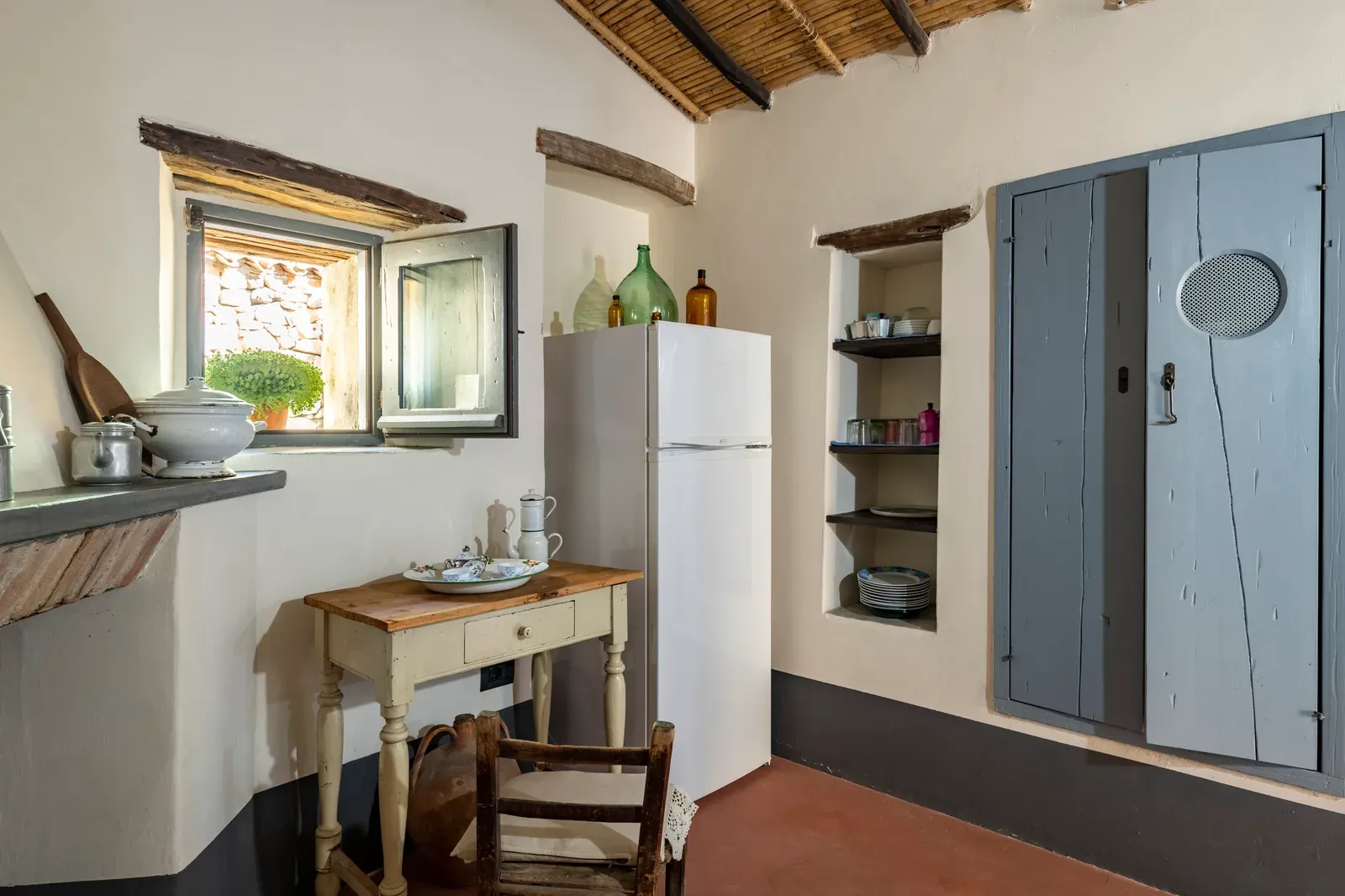 Angolo cucina con frigorifero, mensole e porta azzurra