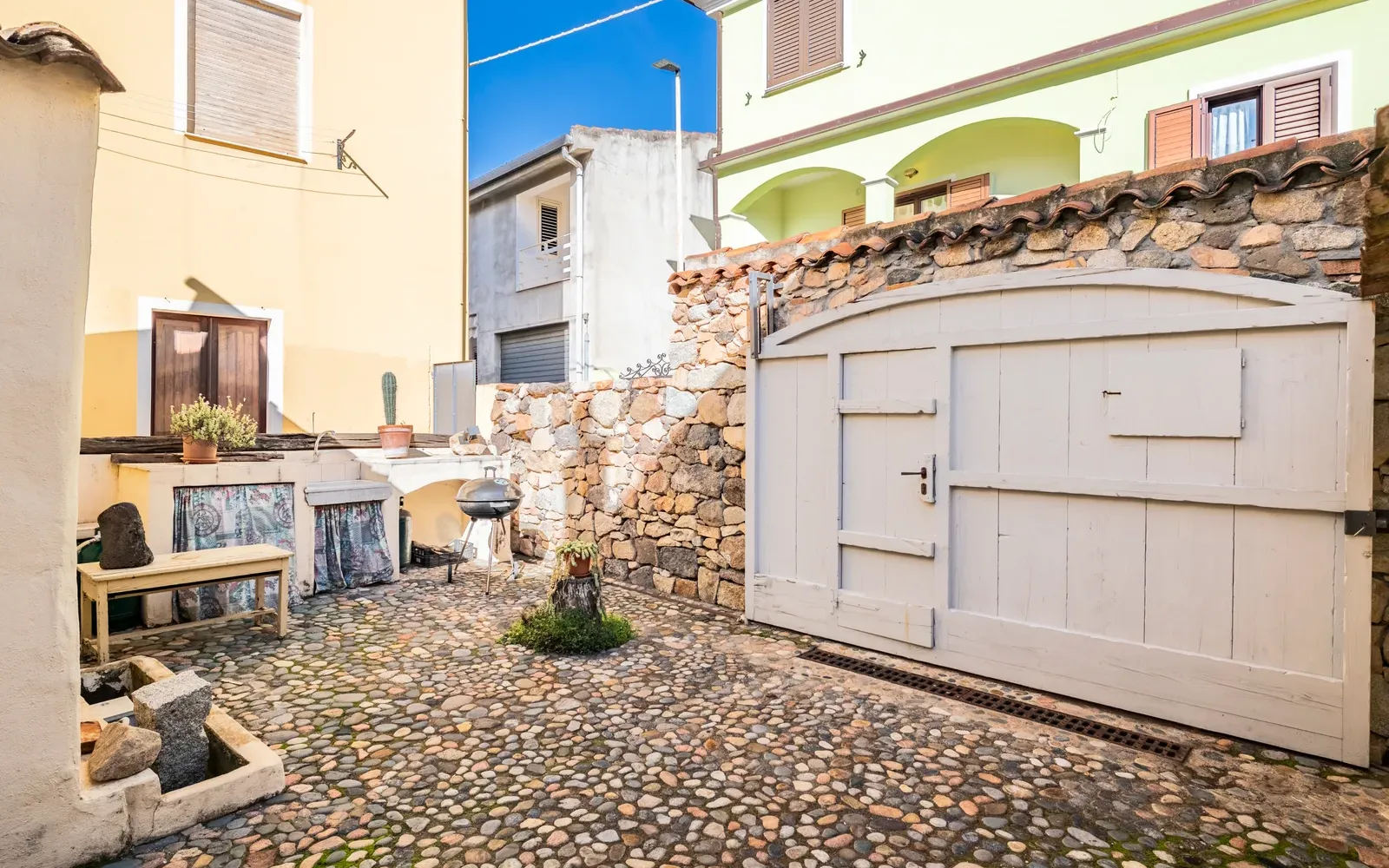 Il cortile con il muro in pietra e la porta ad arco