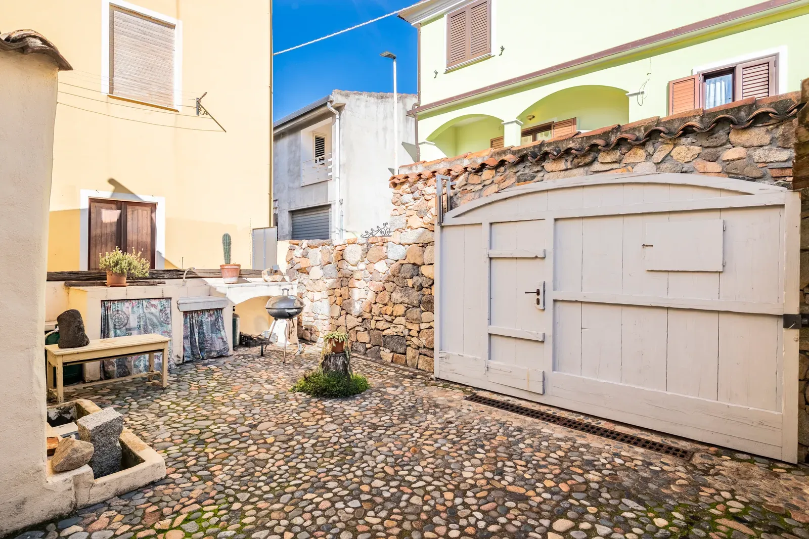 Il cortile con il muro in pietra e la porta ad arco