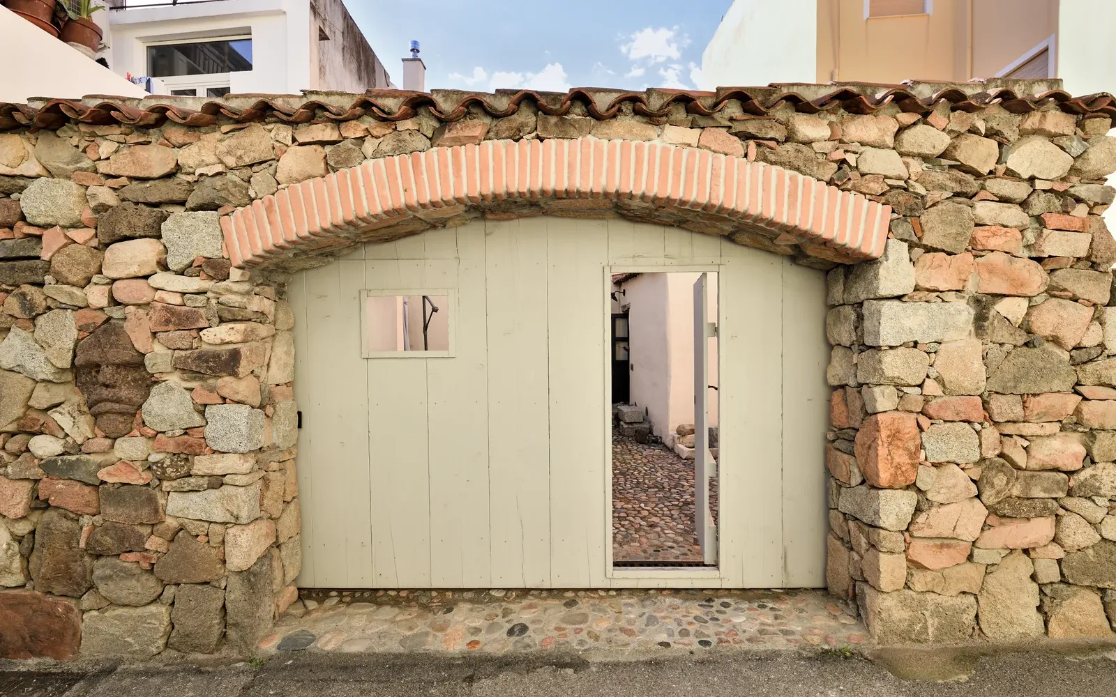 La porta ad arco nel muro in pietra che dà sul cortile