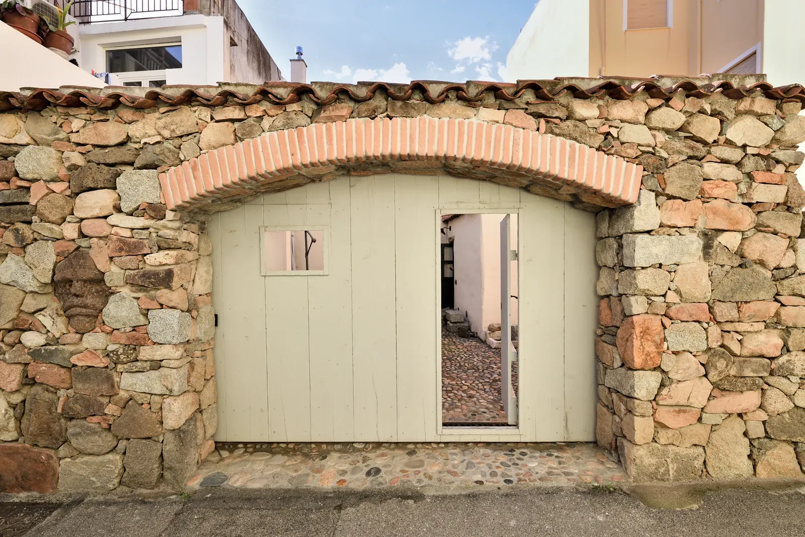 La porta ad arco nel muro in pietra che dà sul cortile
