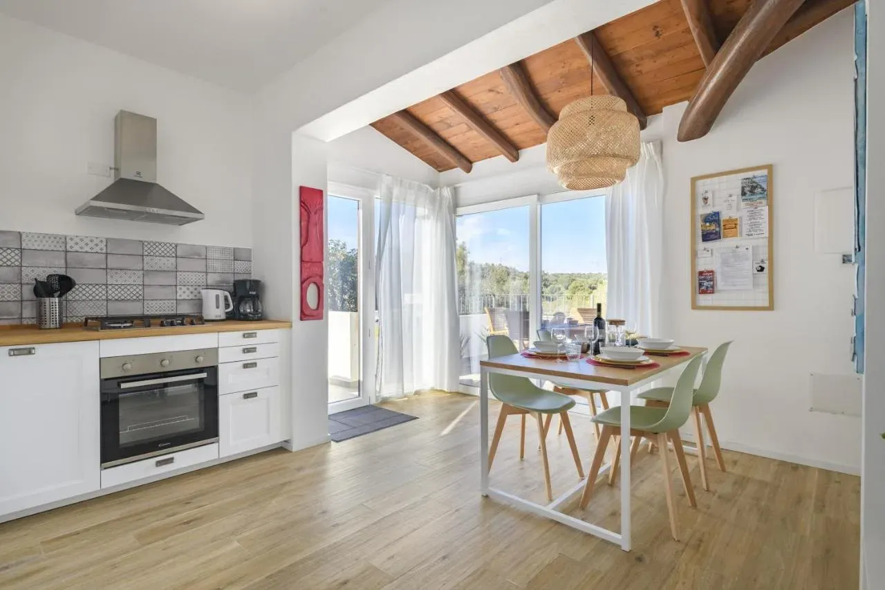Cucina bianca e zona pranzo sotto il soffitto in legno