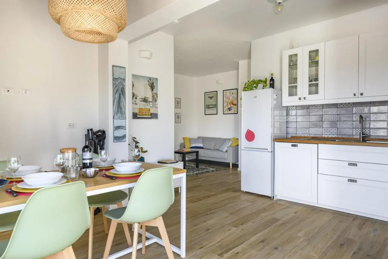 Zona pranzo con sedie verdi e cucina sullo sfondo